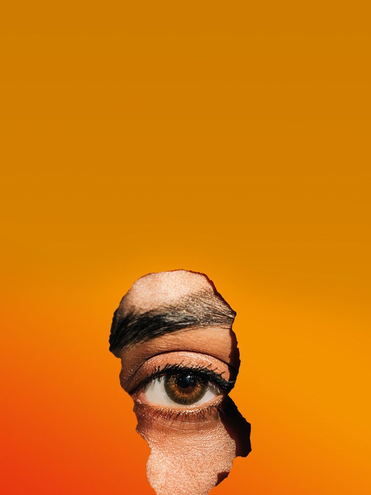 Ein Auge blickt durch einen Riss in orangem Papier