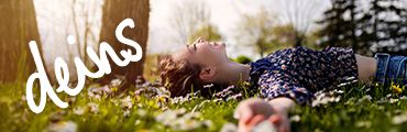 Person liegt entspannt auf einer Wiese mit Blumen, Schriftzug "deins" steht oben rechts.
