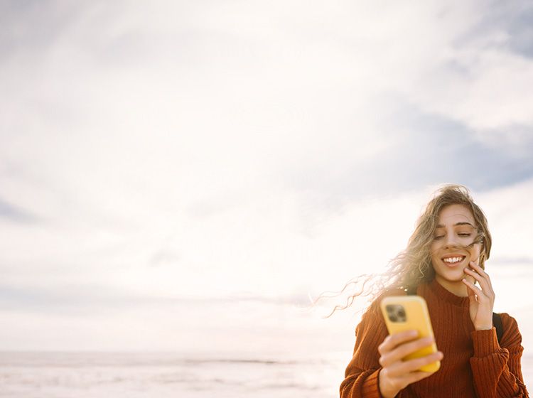 Junges Mädchen schaut auf ihr Handy und lächelt