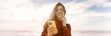 Junges Mädchen schaut auf ihr Handy und lächelt