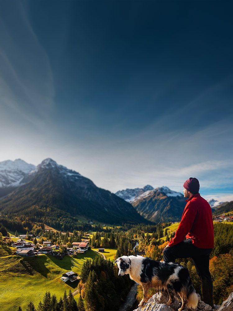 Mann mit Hund blickt von einem Felsen auf ein Alpendorf. Im Bild steht: "A1 Glasfaser – bald auch bei dir! Surfe mit bis zu 1000 Mbit/s im Up- und Download. Die ersten 3 Monate sind gratis! Genau deins!"
