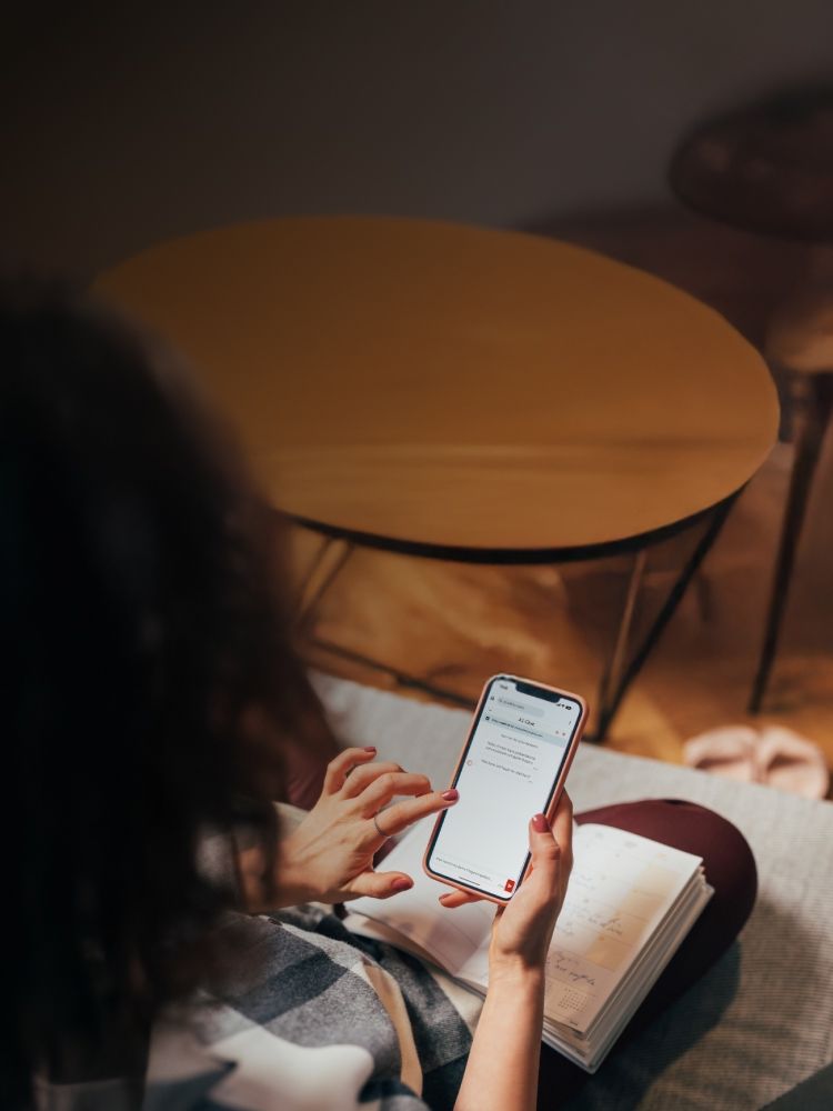 Person hält Smartphone mit geöffneter Chat-App in der Hand, daneben liegt ein aufgeklappter Kalender.