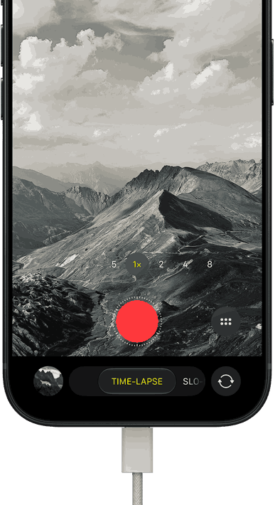 iPhone 18 Pro, Vorderseite, das Display zeigt eine Berglandschaft, mit der Kamera Modus Überlagerung im Zeitraffer Modus, mit dem Netzkabel am Ladeanschluss