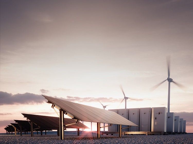 Solaranlagen und Windkraftanlagen bei Sonnenuntergang, daneben Batteriespeicher.