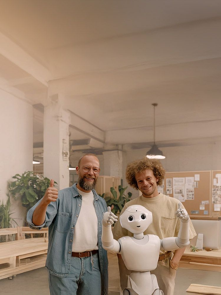 Zwei Personen stehen neben einem humanoiden Roboter in einem modernen Büro und zeigen Daumen hoch.